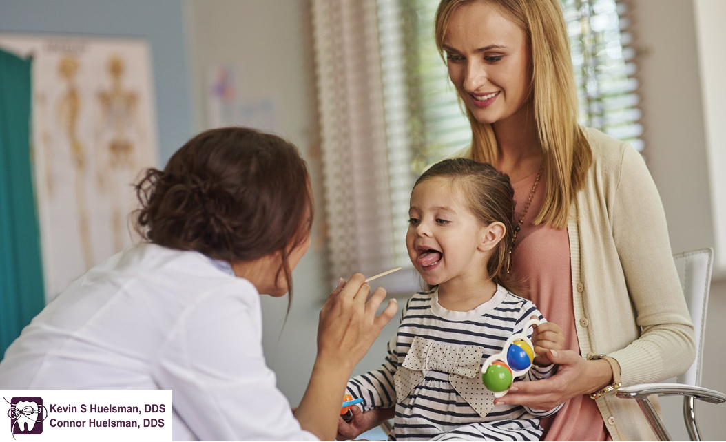 Child having a dental checkup by dentist while sitting beside her mother